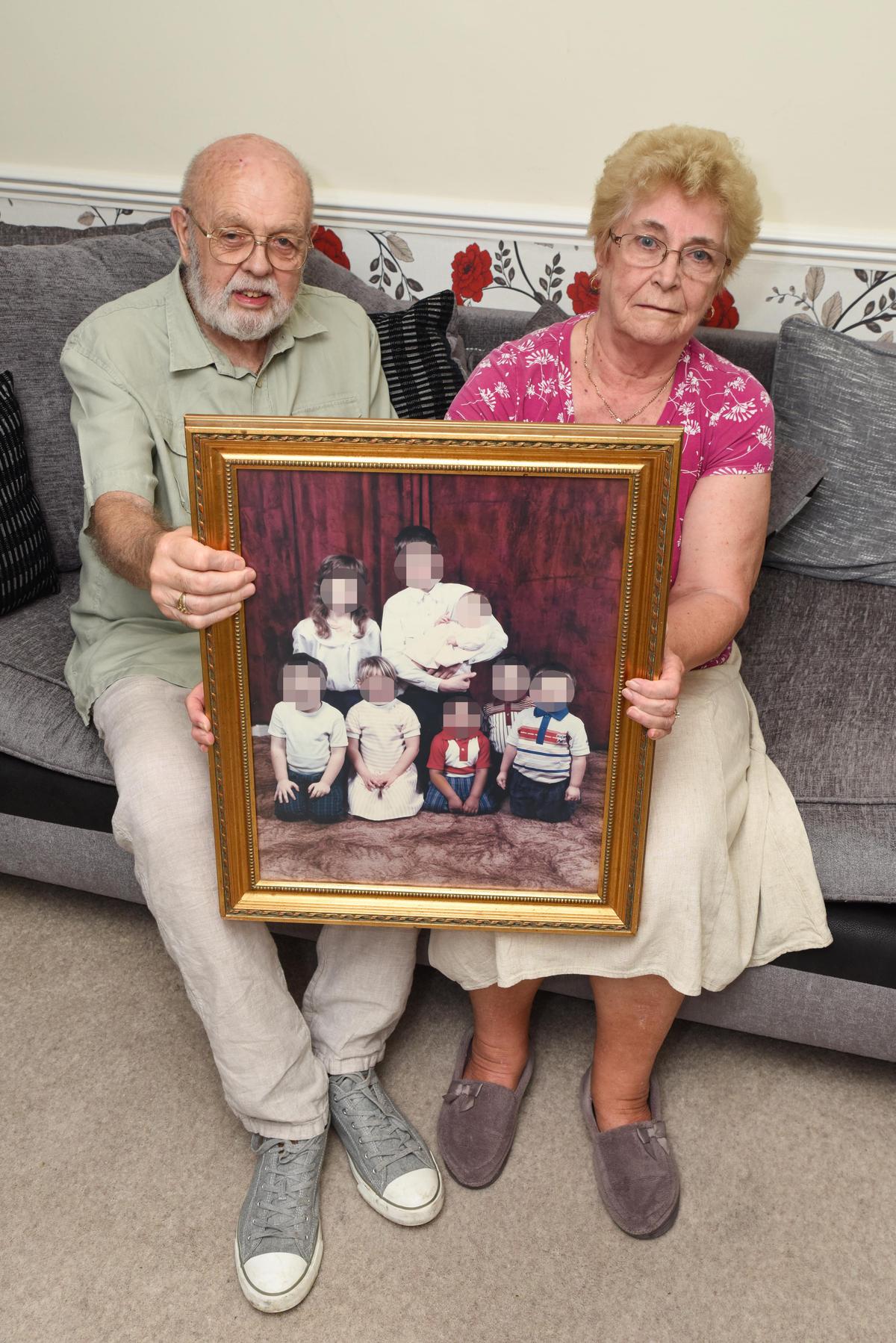 William Foster and his wife, Jean, holding a pixelated image of some of their fostered children on June 17, 2019. (Caters News)