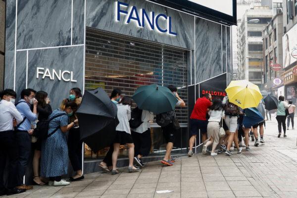 People take cover as riot police use pepper-spray during a protest as a second reading of a controversial national anthem law takes place in Hong Kong, China, on May 27, 2020. (Tyrone Siu/Reuters)