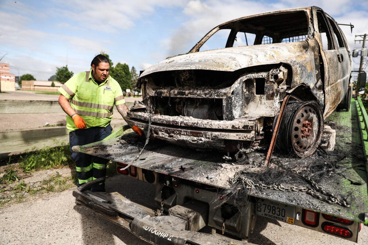 An employee for Rapid Recovery picks up his fourth burned-out vehicle within three hours after a night of protests and violence following the death of George Floyd, in Minneapolis, Minn., on May 29, 2020. (Charlotte Cuthbertson/The Epoch Times)