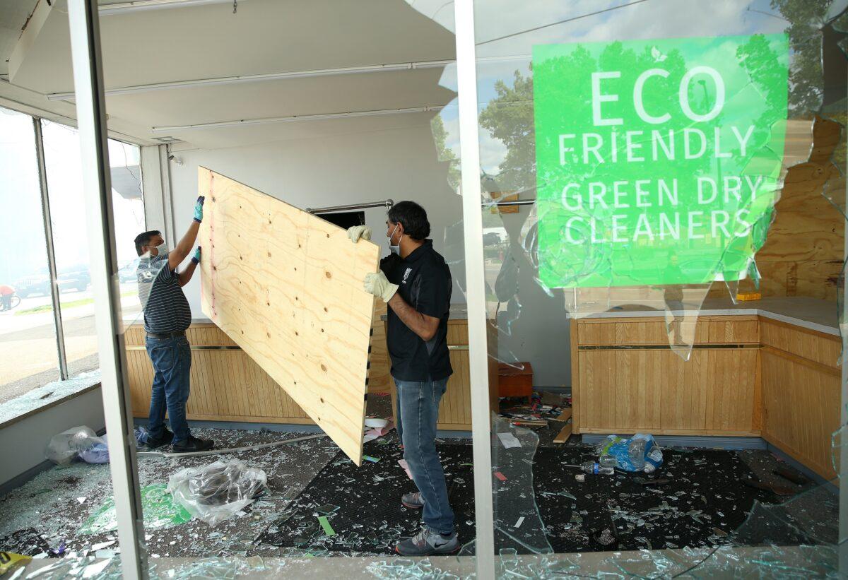 Two men begin to board up a vandalized dry cleaning store after a night of protests and violence in Minneapolis, Minn. on May 29, 2020. (Scott Olson/Getty Images)