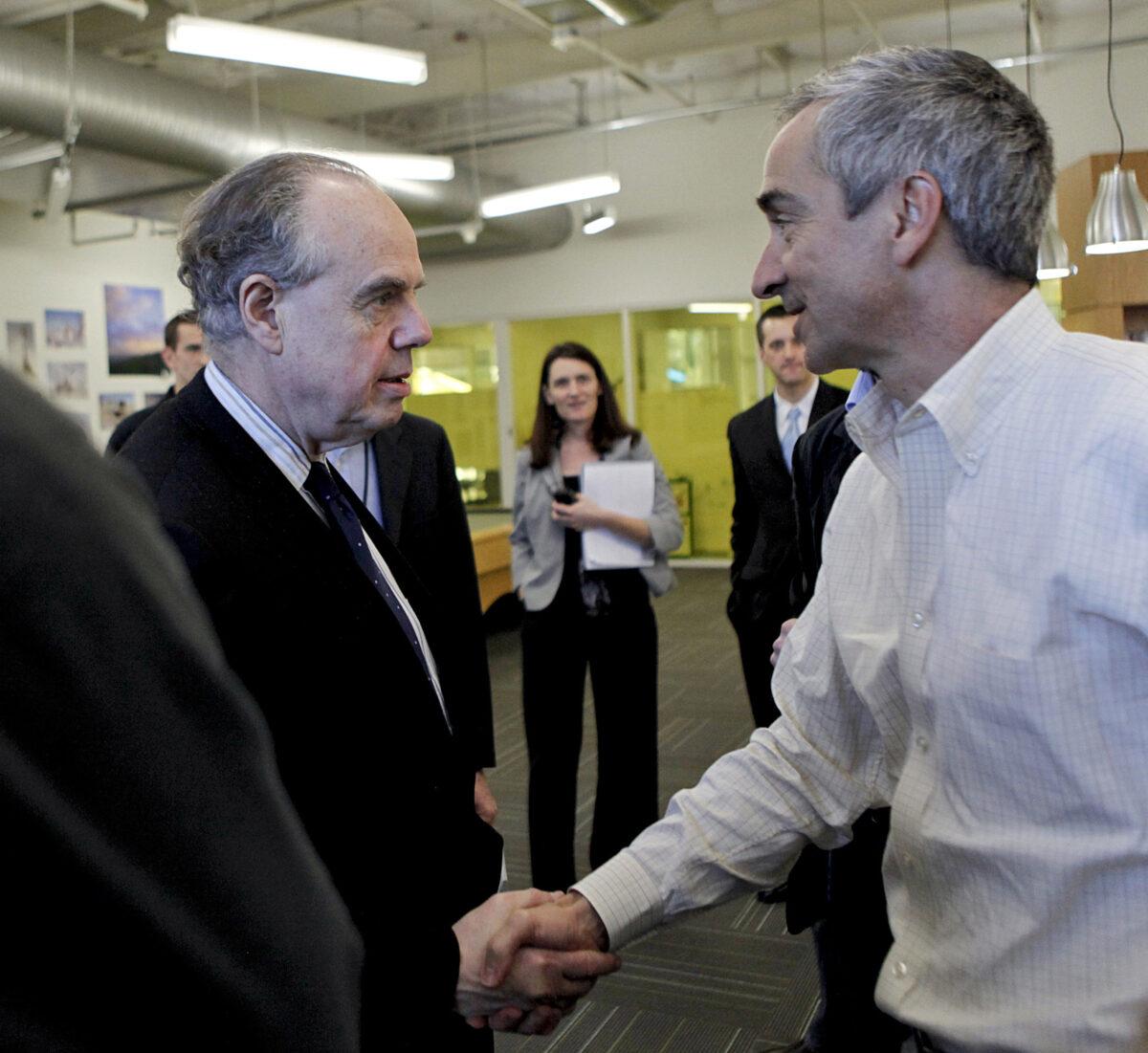 In this file photo, Patrick Pichette, then-CFO at Google (R) shakes hands with French Minister for Culture and Communication Frederic Mitterrand (L) at Google's headquarters in Mountain View, Calif., on March 11, 2011. (Ryan Anson/AFP/Getty Images)