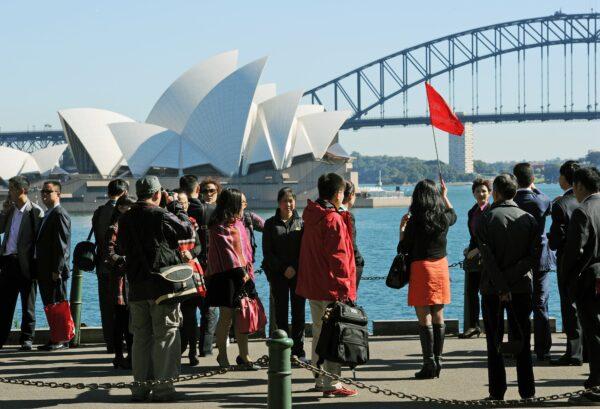 A group of Asian tourists arrive to have their photograph taken in front of the Sydney Opera House and Harbour Bridge, in this photo taken on May 8, 2012. (Greg Wood/AFP/GettyImages)