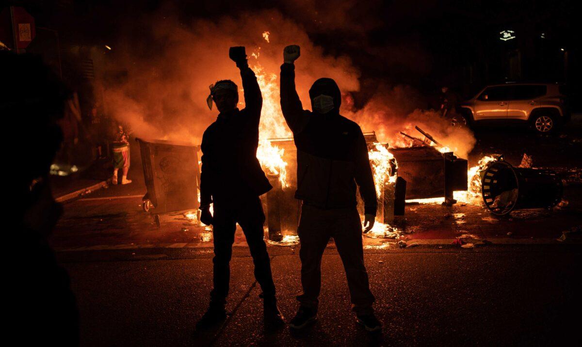 Rioters raise their fists as a fire burns in the street after clashes with law enforcement near the Seattle Police Department's East Precinct, in Seattle, on June 8, 2020. (David Ryder/Getty Images)