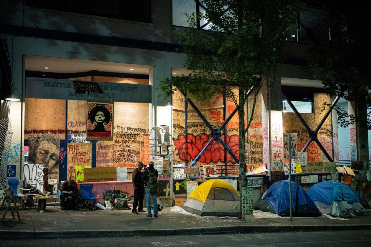People stand near tents outside the abandoned Seattle Police Department precinct in the so-called autonomous zone in Seattle, Wash., on June 23, 2020. (David Ryder/Getty Images)