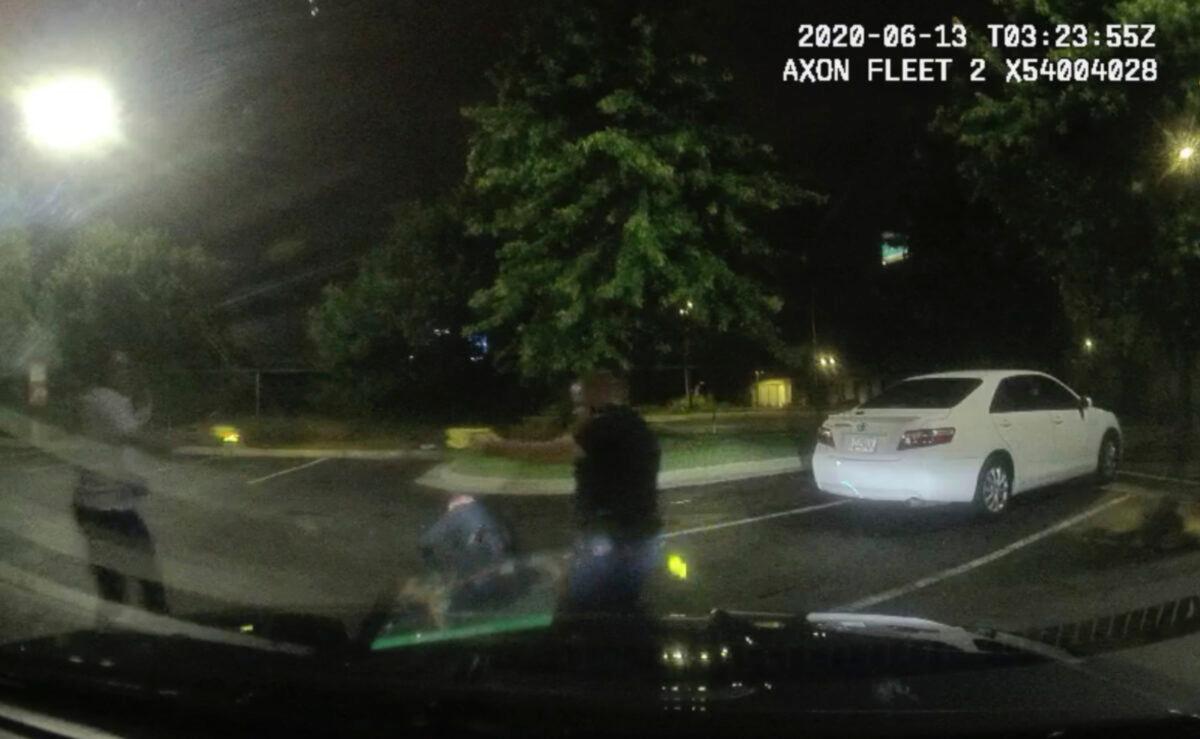 Rayshard Brooks (L) and Officer Garrett Rolfe pointing stun guns at one another, while Officer Devin Brosnan is seen getting up after a struggle among the three men in the parking lot of a Wendy's restaurant, in Atlanta, Ga., early June 13, 2020. (Atlanta Police Department via AP)