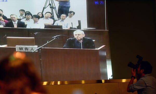 Journalists follow the progress on a television screen of the trial of British investigator Peter Humphrey (C) linked to beleaguered pharmaceutical giant GSK and his wife, at the Shanghai Intermediate Court on Aug. 8, 2014. (Johannes Eisele /AFP via Getty Images)