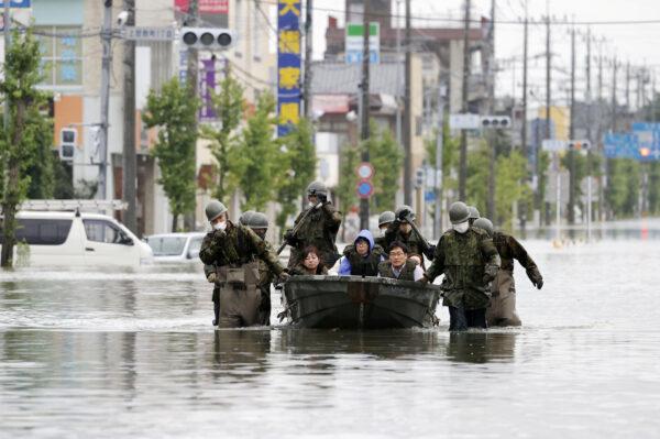 Local residents are rescued by Japan Self-Defense Force soldiers using a boat on a flooded road, caused by heavy rain in Omuta, Fukuoka prefecture, southern Japan, on July 7, 2020. (Kyodo/via Reuters)
