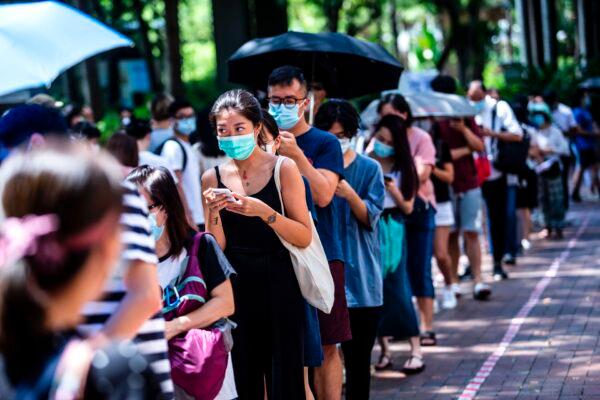 A woman (center L) uses her phone while waiting to vote during primary elections in Hong Kong on July 12, 2020. (Isaac Lawrence/AFP via Getty Images)