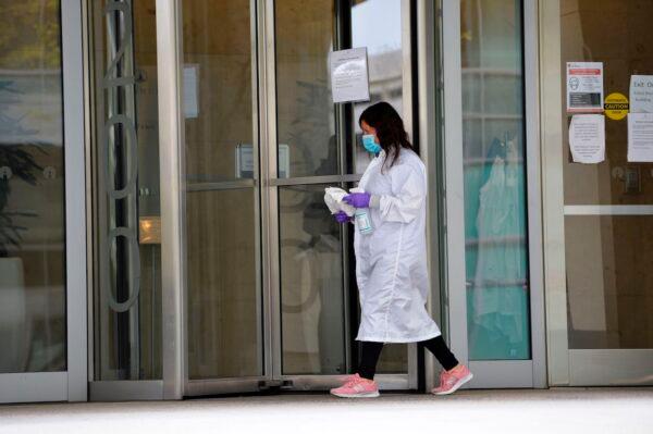 A women cleans the entrance doors to Moderna headquarters in Cambridge, Massachusetts, on May 18, 2020. (Joseph Prezioso/AFP via Getty Images)