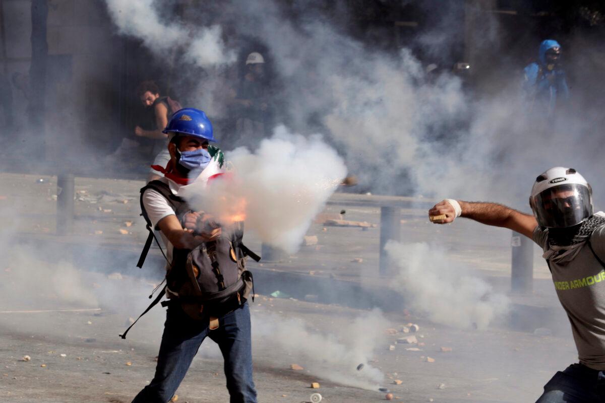 Anti-government protesters clash with riot police officers during a protest against the political elites and the government after this week's deadly explosion at Beirut port which devastated large parts of the capital and killed more than 160 people, in Beirut, Lebanon, on Aug. 8, 2020. (Hassan Ammar/AP Photo)