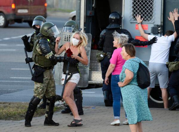 A woman fights with a police officer as the other police officers detain an opposition supporter protesting the election results as protesters encounter aggressive police tactics in the capital of Minsk, Belarus, on Aug. 11, 2020. (AP Photo)
