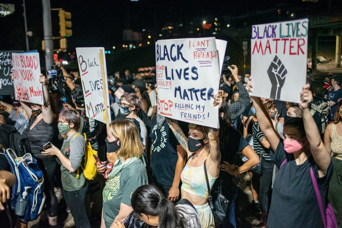 People hold up signs outside Austin Police Department after a vigil for Garrett Foster, a Black Lives Matter protester who was shot dead after allegedly brandishing his firearm at a driver, in Austin, Texas, on July 26, 2020. (Sergio Flores/Getty Images)