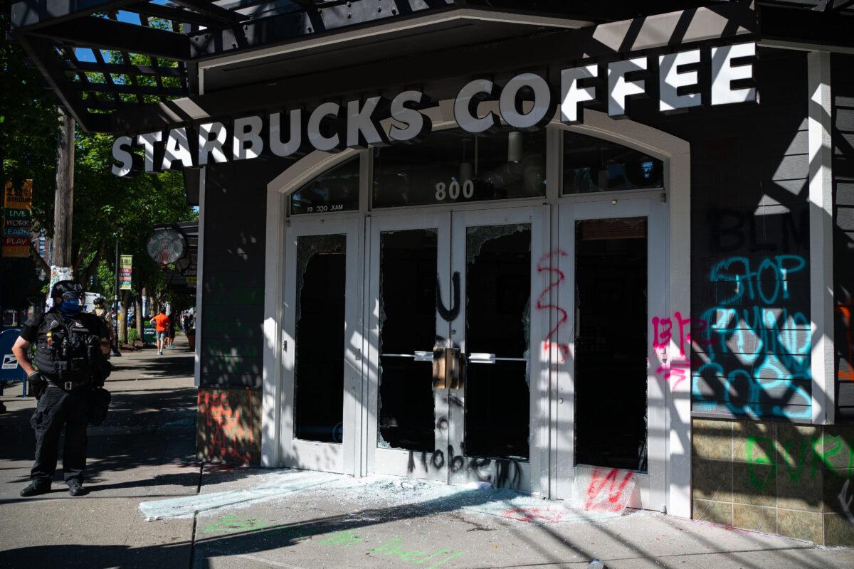 A police officer keeps watch after rioters smashed windows and vandalized a Starbucks store, in Seattle, Wash., on July 25, 2020. (David Ryder/Getty Images)