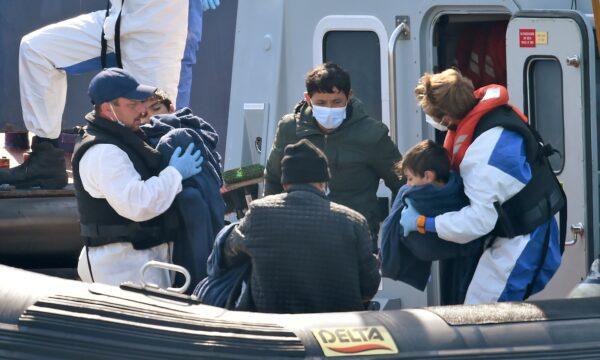 UK Border Force officers help migrants with children, believed to have been picked up from boats in the Channel, disembark from coastal patrol vessel "HMC Hunter," in the port of Dover, on Aug. 9, 2020. (Glyn Kirk/AFP via Getty Images)