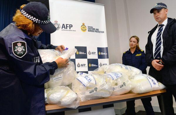 An Australian Federal Police officer (L) inspects seized methamphetamine after Australian authorities found Aus$180 million (US$162 million) of the drug stashed in a consignment of kayaks from China in Sydney on February 12, 2014. (WILLIAM WEST/Getty Images)