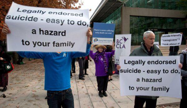 A woman (C) holds a sign in support of assisted suicide while others demonstrate against it outside the B.C. Court of Appeal on Oct. 10, 2013. (Darryl Dyck/The Canadian Press)