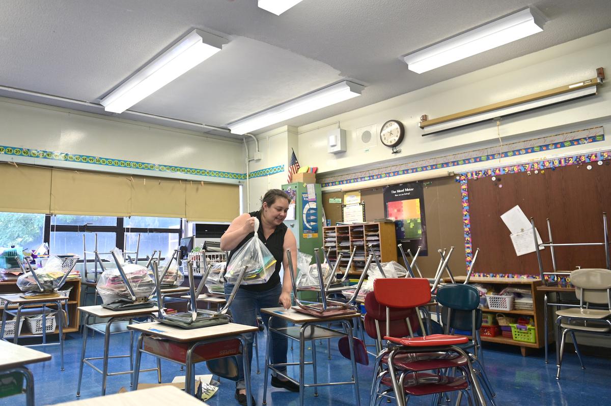 A teacher at Yung Wing Elementary School moves desks and chairs in her classroom to socially distance desks for the 2020–21 school year in New York on Aug. 17, 2020. (Michael Loccisano/Getty Images)