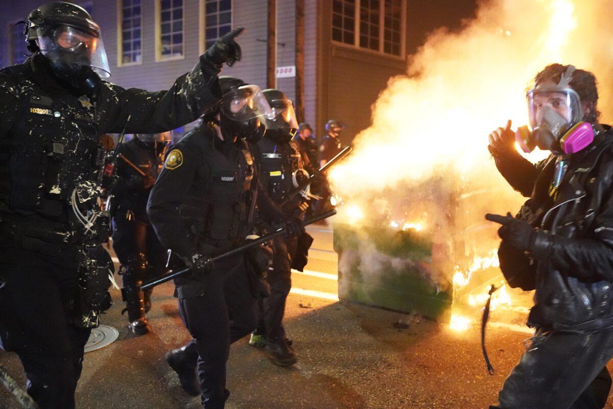 Portland police officers disperse rioters past a dumpster fire near the Immigration and Customs Enforcement detention facility in Portland, Ore., early Aug. 21, 2020. (Nathan Howard/Getty Images)
