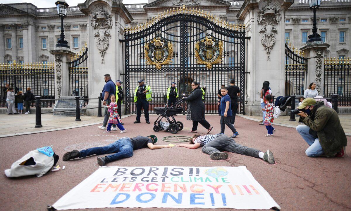 A family walk past as activists take part in a demonstration outside Buckingham Palace, as part of protests by the Extinction Rebellion climate change group, in central London, on Sept. 5, 2020 (Justin Tallis/AFP via Getty Images)