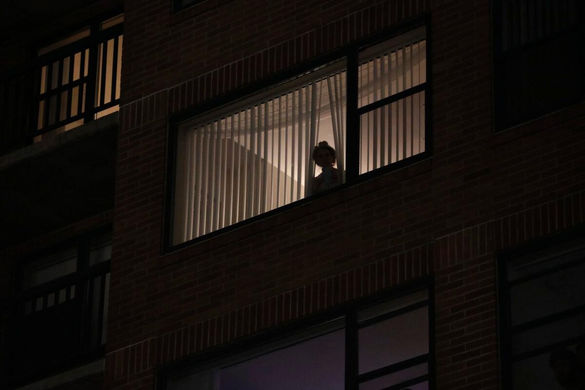A woman looks out her window while protesters and police clash near the Mark O. Hatfield Courthouse in Portland, Ore., on Sept. 26, 2020. (Allison Dinner/AP Photo)
