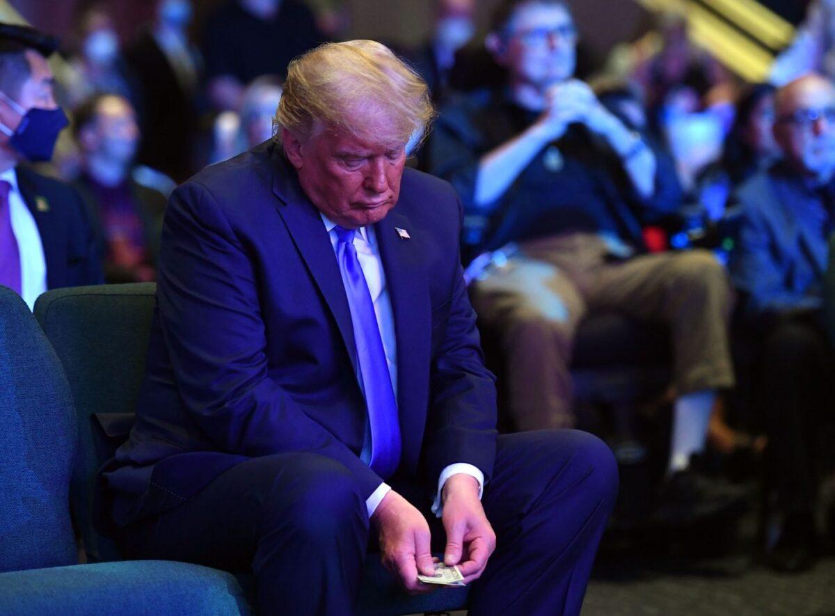 President Donald Trump counts money before making an offering, as he attends services at the International Church of Las Vegas in Las Vegas, Nevada on Oct. 18, 2020. (MANDEL NGAN/AFP via Getty Images)