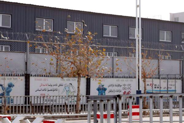 In this Dec. 5, 2018, photo, two layers of barbed wire fencing ring the "Hotan City apparel employment training base," where Hetian Taida has a factory in Hotan in western China's Xinjiang region. This is one of a growing number of internment camps in the Xinjiang region, where by some estimates 1 million Muslims are being detained, forced to give up their language and their religion, and subject to political indoctrination. (AP Photo/Ng Han Guan)