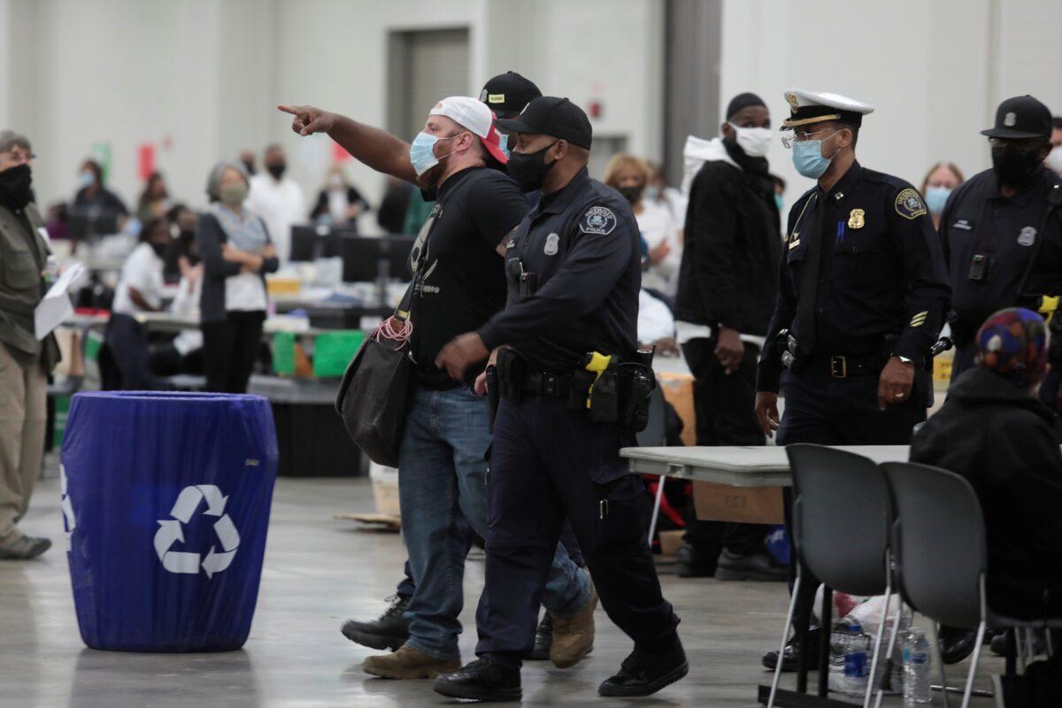 Detroit police escort a poll challenger out after he refused to leave, due to room capacity, at the TCF Center after Election Day in Detroit, Mich., Nov. 4, 2020. (Rebecca Cook/Reuters)