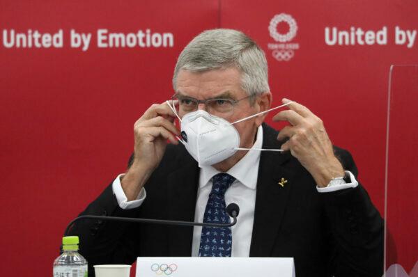 Thomas Bach, International Olympic Committee president, puts his mask on after a press conference in Tokyo on Nov. 16, 2020. (Du Xiaoyi/Pool)