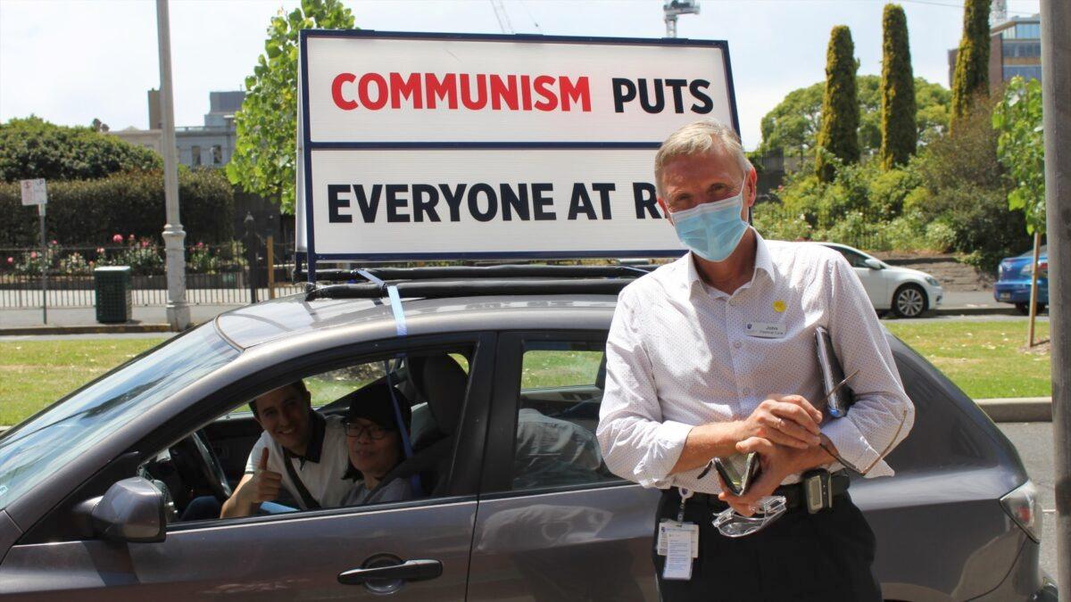 A man by the name of John takes a photo in front a car with a sign that reads "Communism puts everyone at risk" during an end CCP car rally in Melbourne, Australia on Nov. 22, 2020. (The Epoch Times)