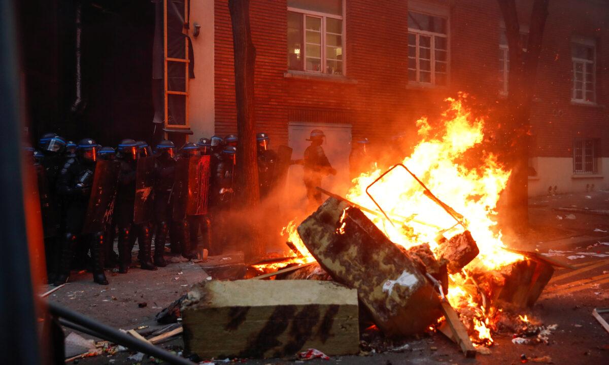 Police officers stand guard near a burning barricade during a protest against the "Global Security Bill'' in Paris on Dec. 5, 2020. (Gonzalo Fuentes/Reuters)