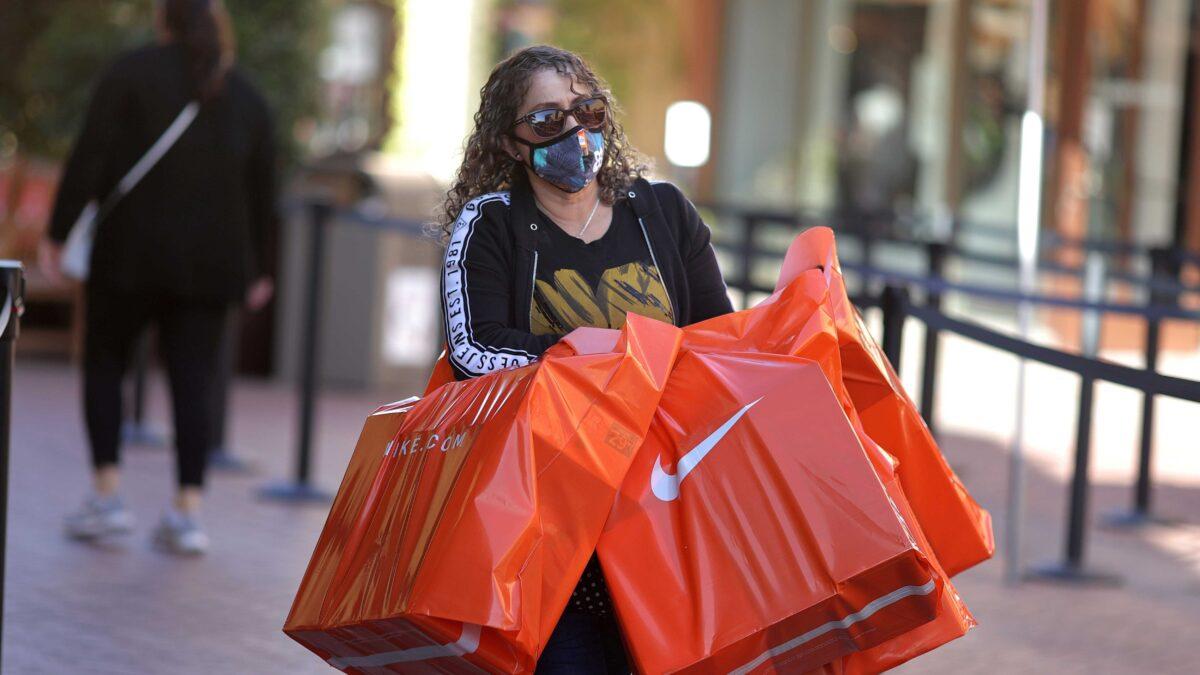 A woman carries Nike shopping bags at the Citadel Outlet mall in Commerce, Calif., on Dec. 3, 2020. (Lucy Nicholson/Reuters)