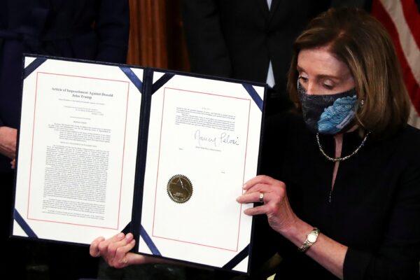 House Speaker Nancy Pelosi (D-Calif.) shows the article of impeachment against President Donald Trump after signing it in an engrossment ceremony, at the U.S. Capitol in Washington on Jan. 13, 2021. (Leah Millis/Reuters)