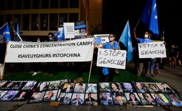 Protesters stand behind a display of photographs of prominent Uighur intellectuals detained by China as they gather across from the Chinese Consulate in Los Angeles, Calif., on Oct. 1, 2020. (Frederic J. Brown/AFP via Getty Images)