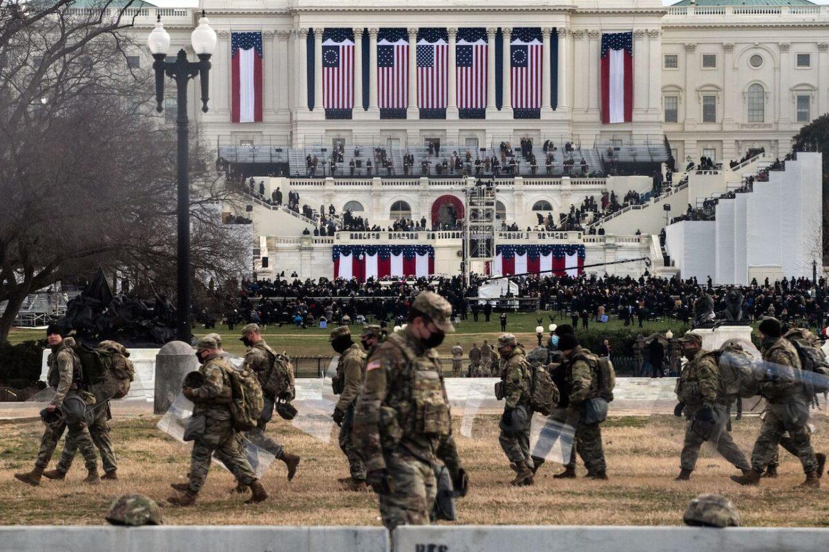 National Guard troops carry riot shields as they assume positions in the vicinity of the US Capitol as the Inauguration of Joe Biden in Washington, on Jan. 20, 2021. (Roberto Schmidt/AFP via Getty Images)