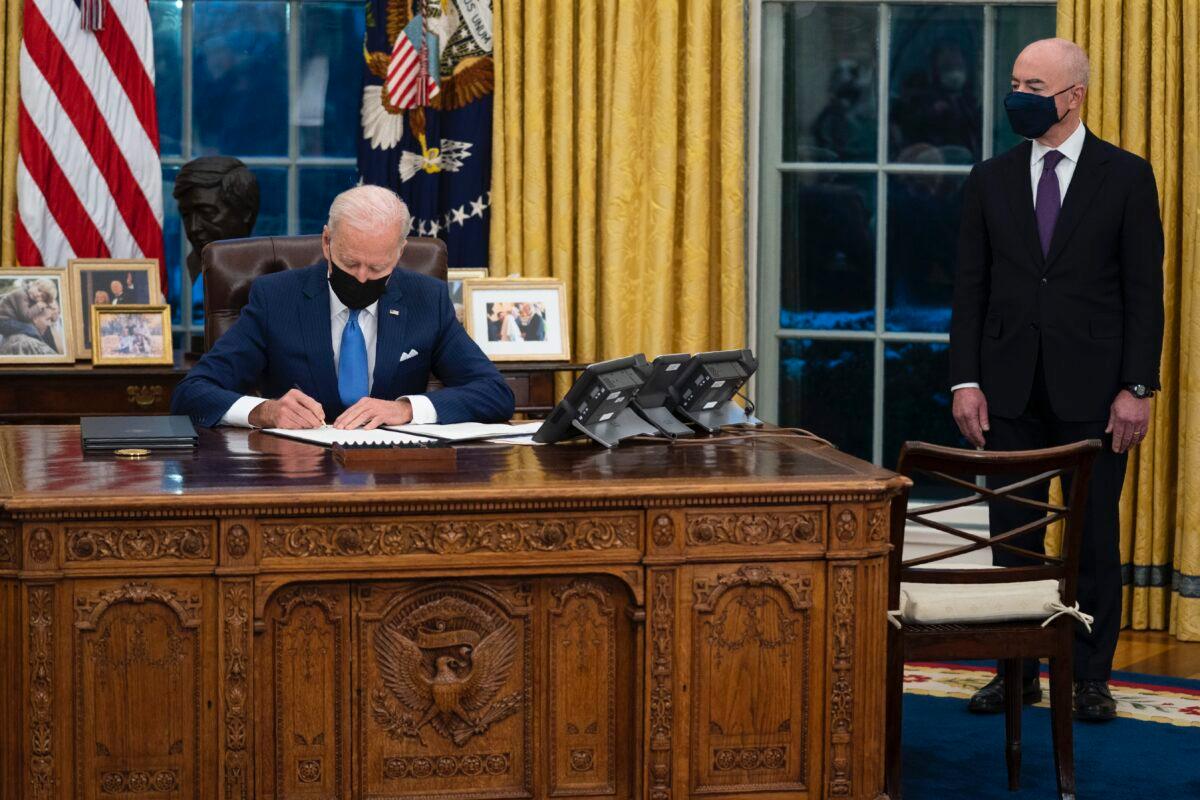 Secretary of Homeland Security Alejandro Mayorkas looks on as President Joe Biden signs an executive order on immigration, in the Oval Office of the White House in Washington on Feb. 2, 2021. (Evan Vucci/AP Photo)