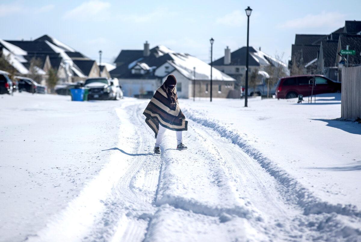 A man walks to his friend's home in a neighborhood without electricity as snow covers the BlackHawk neighborhood in Pflugerville, Texas, on Feb. 15, 2021. (Bronte Wittpenn/Austin American-Statesman/USA Today Network via Reuters)