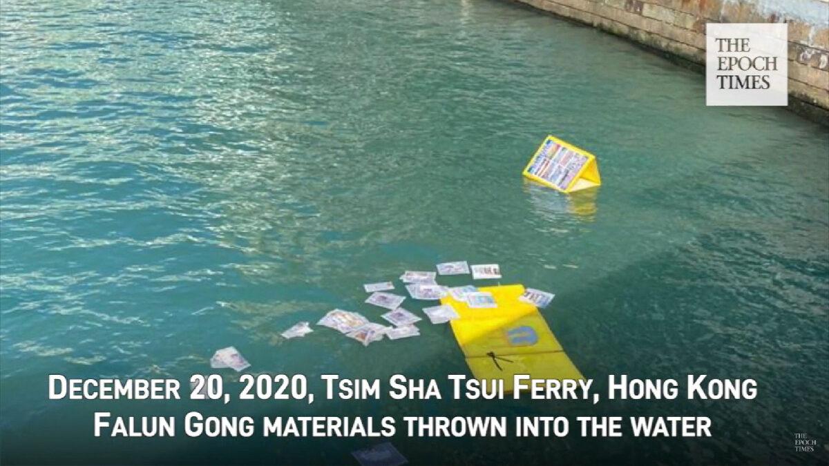 Printouts and display boards from a Falun Gong booth in Tsim Sha Tsui are thrown into a nearby harbor on Dec. 20, 2020. (Screenshot via YouTube)