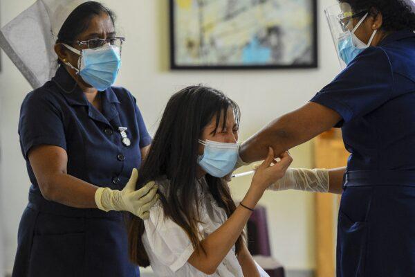 A health worker inoculates the Chinese-made Sinopharm vaccine to a Chinese national living in Sri Lanka, at the Colombo Port City project premises, in Colombo, Sri Lanka on April 6, 2021. (Ishara S. Kodikara/AFP via Getty Images)