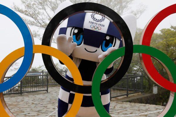 Tokyo 2020 Olympic Games mascot Miraitowa poses with a display of Olympic Symbol after an unveiling ceremony of the symbol on Mt. Takao in Hachioji, west of Tokyo to mark 100 days before the start of the Olympic Games, on April 14, 2021. (Kim Kyung-Hoon/Pool Photo via AP)