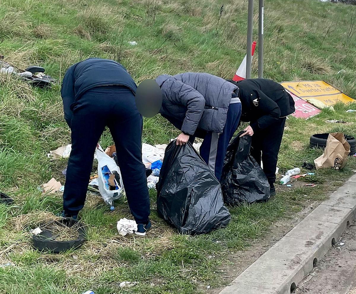 The group of fly-tippers picking up the rubbish that they dumped on the side of the M6 motorway in Staffordshire, England, on March 28. (SWNS)