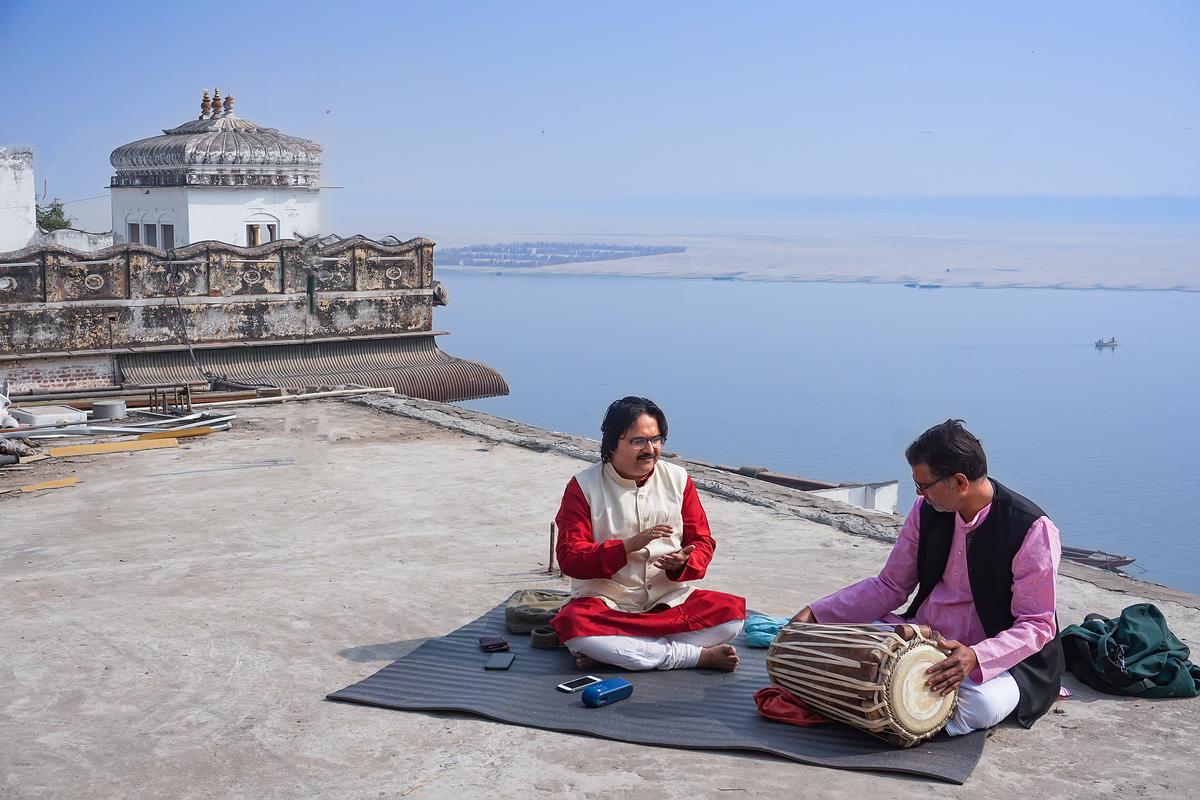 Classical vocalist Supriyo Maitro (L) and pakhawaj (barrel drum) player Ravishankar Shukla (R) practice Dhrupad style of Indian music at the Assi Ghat with the Ganges River in the background, in the ancient city of Kashi on Feb. 19, 2021. (Venus Upadhayaya/Epoch Times)