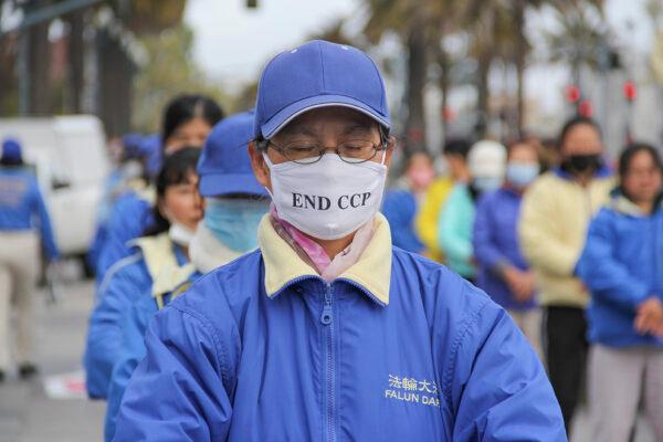 Falun Gong practitioners meditate during a rally to commemorate the peaceful appeal and raise awareness about the persecution still happening in China today in front of the Ferry Building in San Francisco on Apr. 24, 2021. (David Lam/The Epoch Times)