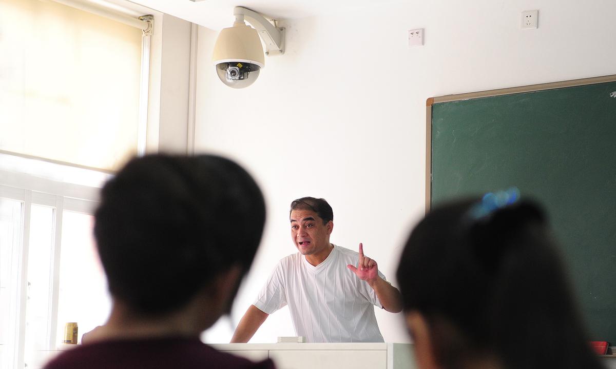 Mr. Ilham Tohti, a Uyghur professor of economics, delivers his lecture under a security surveillance camera mounted above the teacher's podium in a classroom in Beijing on June 12, 2010. (Frederic J. Brown/AFP via Getty Images)