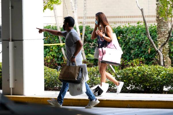 Shoppers walk towards a garage after leaving the Aventura Mall where a shooting left three people injured and several suspects in custody, in Aventura, Fla., on May 8, 2021. (Marta Lavandier/AP Photo)