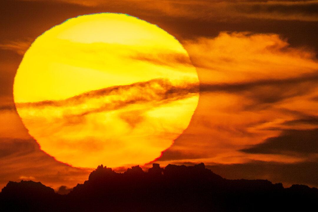 Photographer Captures Surreal Sight of Huge Raging Sun Setting Behind Iconic Rock Formation in UK