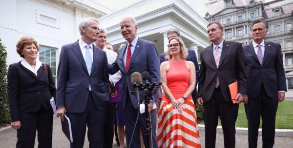 President Joe Biden (C), joined by from left to right, Sens. Jeanne Shaheen (D-N.H.), Rob Portman (R-Ohio), Bill Cassidy (R-La.), Kyrsten Sinema (D-Ariz.), Mark Warner (D-Va.), and Mitt Romney (R-Utah), speaks after the bipartisan group of senators reached a deal on an infrastructure package at the White House on June 24, 2021. (Kevin Dietsch/Getty Images)