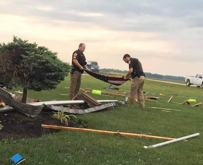 Sergeant Derek Bogenschutz (L) and Deputy Eric Smitley folding an American flag found amidst the debris. (Courtesy of <a href="https://www.facebook.com/JayCountySheriffsOffice/">Jay County Sheriff's Office</a>)