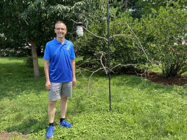 Wade Kammin, owner of Wild Birds Unlimited in Springfield, Illinois, stands by the artificial tree in the side yard of his business. The artificial tree has a container of all-natural cotton product material hanging from a limb. (Tamara Browning)