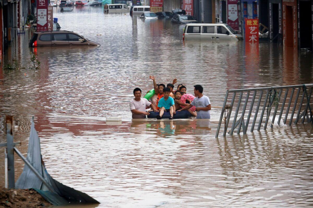 Children sit on a makeshift raft on a flooded road following heavy rainfall in Zhengzhou, Henan Province, China, on July 22, 2021. (Aly Song/Reuters)