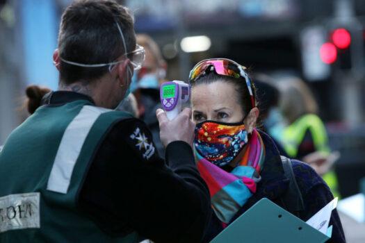 A St John Ambulance staff member takes the temperature of a client arriving at a COVID-19 Vaccination Centre in the CBD in Sydney, Australia, on July 19, 2021. (Lisa Maree Williams/Getty Images)